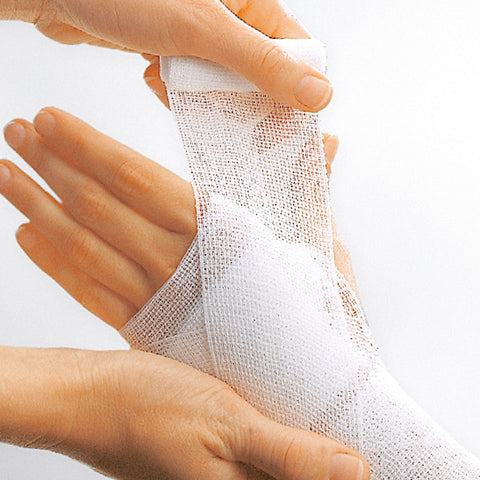 Hand applying white bandage to another hand on a light gray background